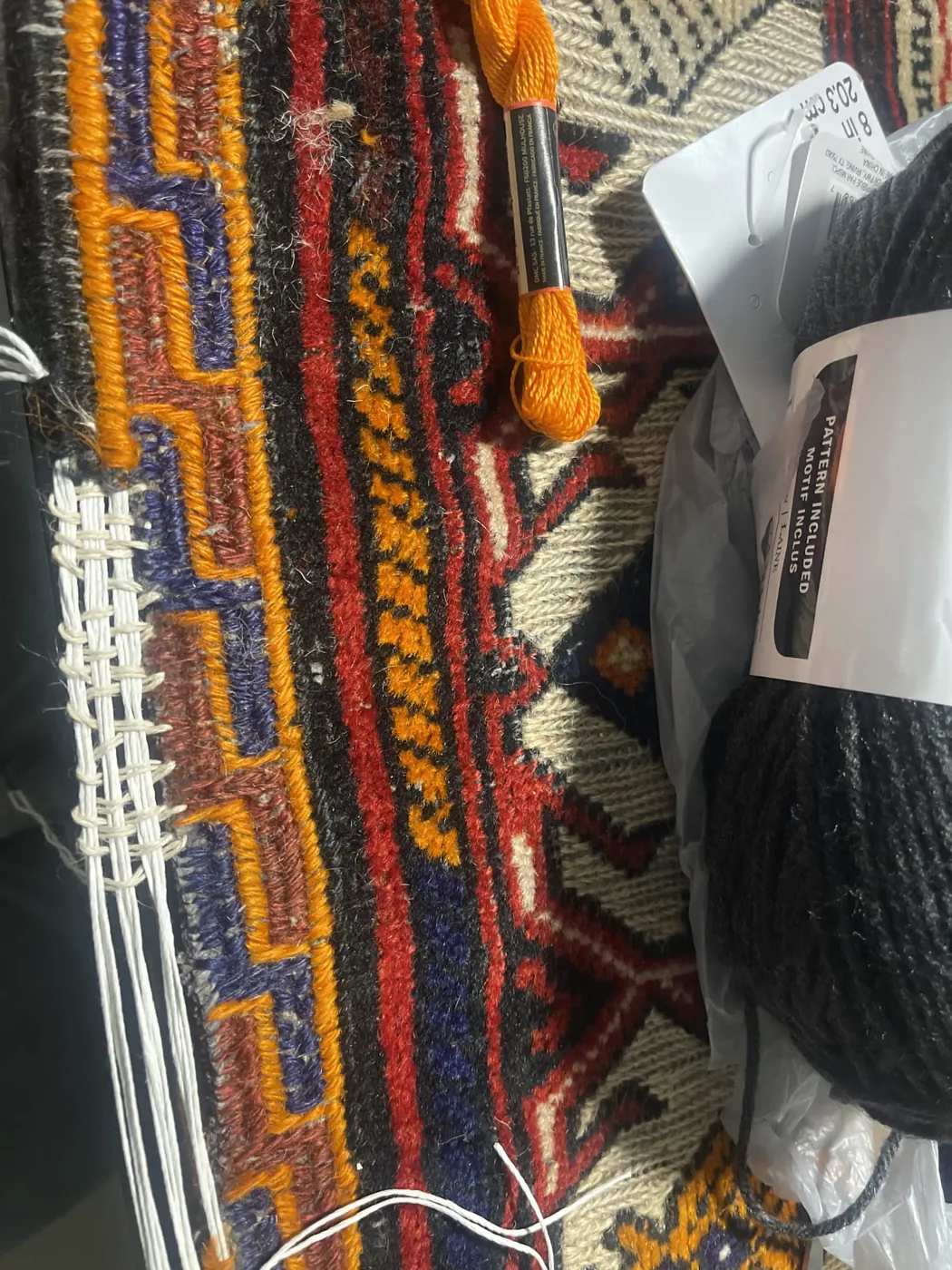 New overcast stitching along the edge of an orange tribal rug