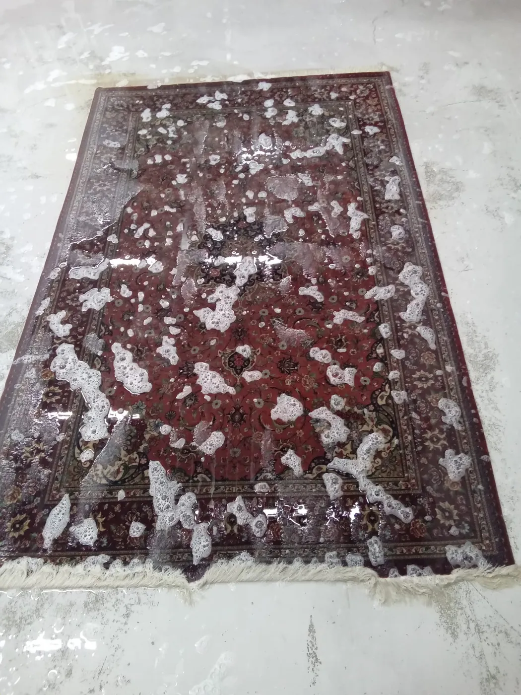 Dark rug showing heavy soiling and staining across the pile