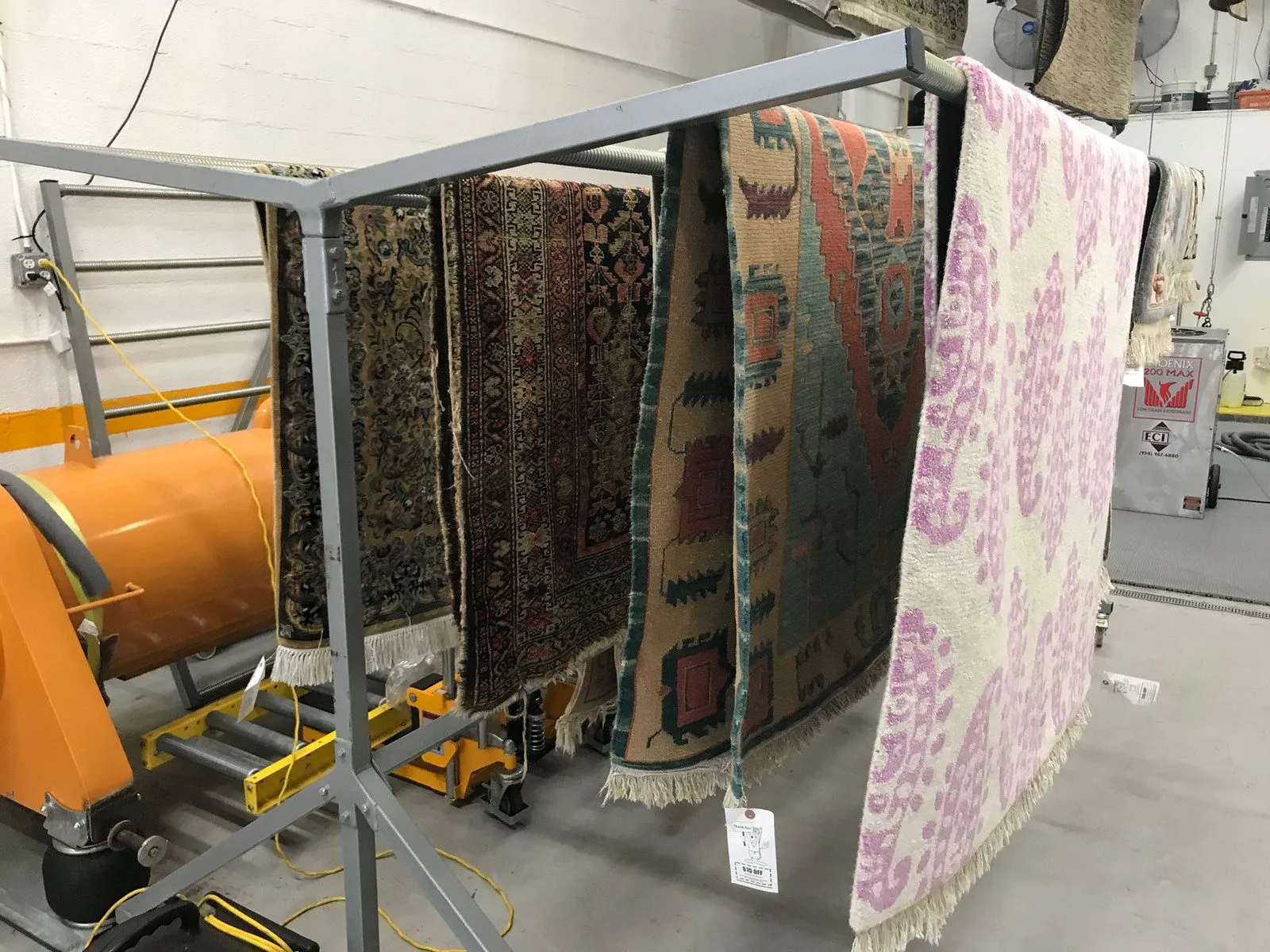 Several area rugs drying on a steel rack at the Fort Lauderdale shop