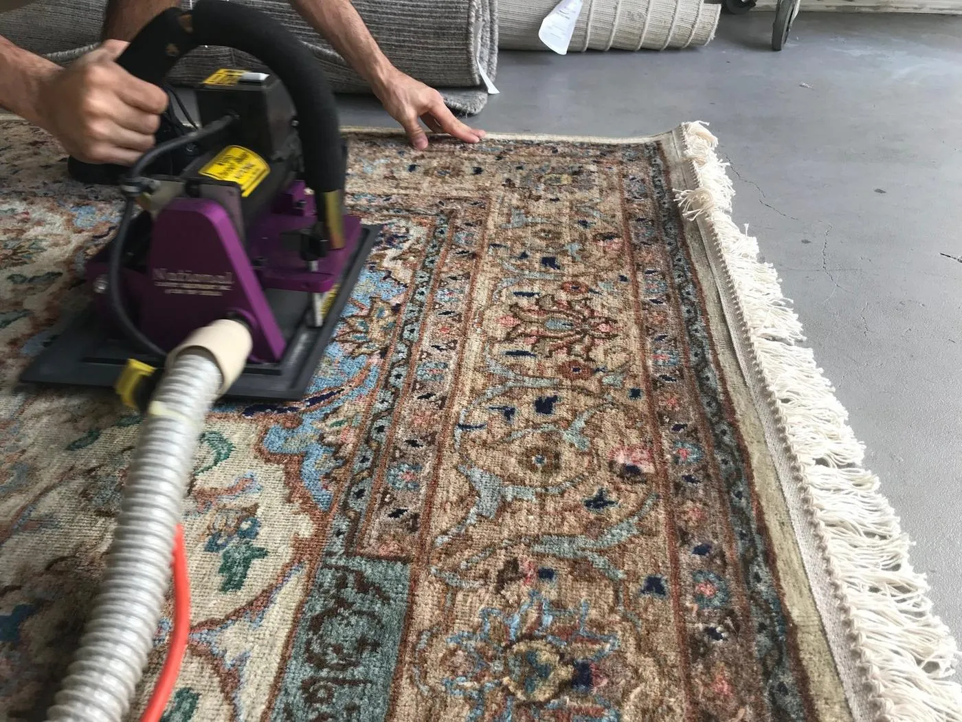 Harmonic vibration dusting machine removing dry soil from an Oriental rug