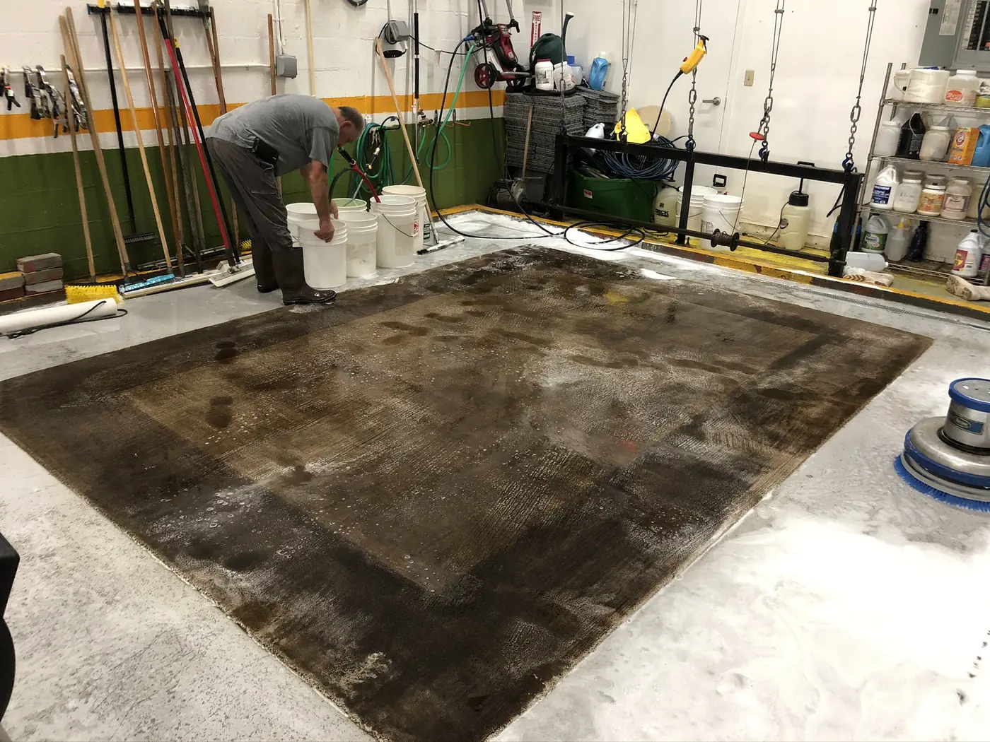 Large dark rug wet on the wash floor with a technician working